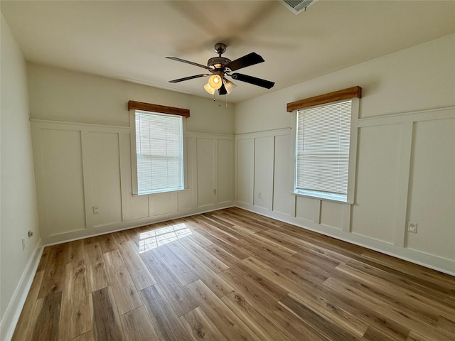 602 E Main St, Kirbyville, TX 75956 - unfurnished bedroom with visible vents, ceiling fan, a decorative wall, a wainscoted wall, and wood finished floors
