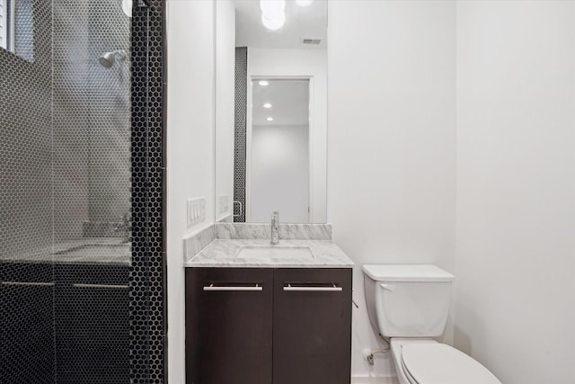 full bathroom with toilet, tiled shower, vanity, and visible vents