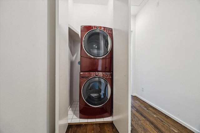 laundry area with laundry area, stacked washer / dryer, wood finished floors, and baseboards