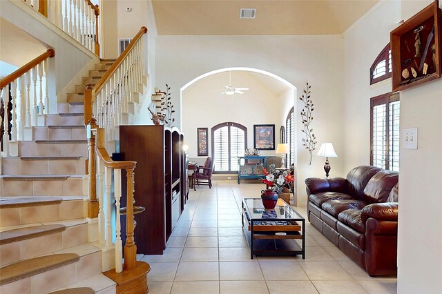 12934 Bristol Berry Dr, Cypress, TX 77429 - living area featuring arched walkways, a high ceiling, tile patterned flooring, ceiling fan, and stairway