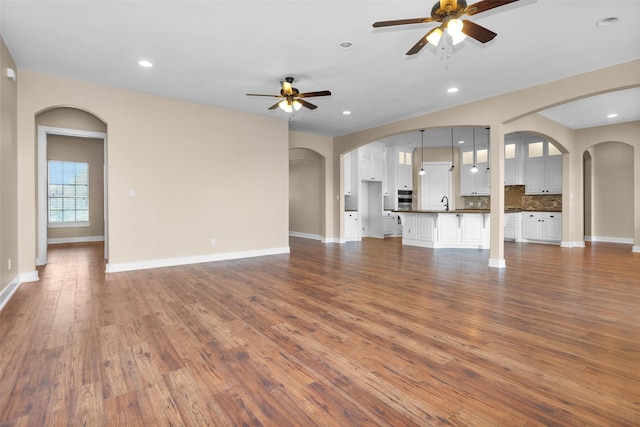 1650 Winding Canyon Ct, Katy, TX 77493 - unfurnished living room featuring baseboards, wood finished floors, a ceiling fan, and arched walkways