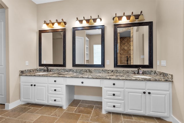1650 Winding Canyon Ct, Katy, TX 77493 - bathroom with baseboards, stone tile floors, double vanity, and a sink
