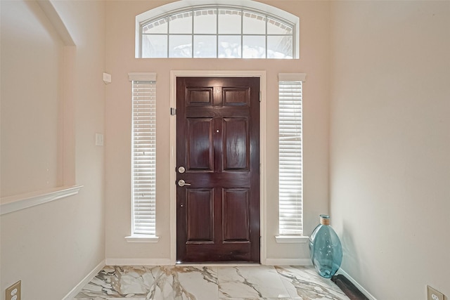 foyer featuring marble finish floor and baseboards