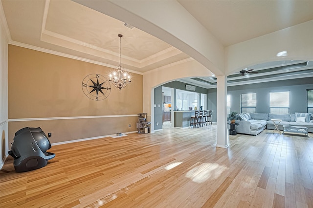 interior space with baseboards, ceiling fan with notable chandelier, hardwood / wood-style flooring, arched walkways, and a raised ceiling