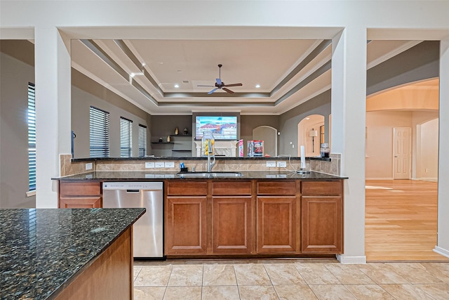 kitchen with brown cabinets, a ceiling fan, a sink, arched walkways, and dishwasher