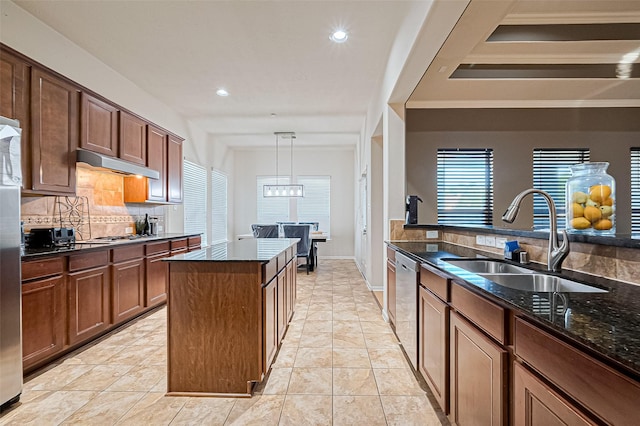 kitchen with a sink, tasteful backsplash, dark stone countertops, under cabinet range hood, and stainless steel dishwasher