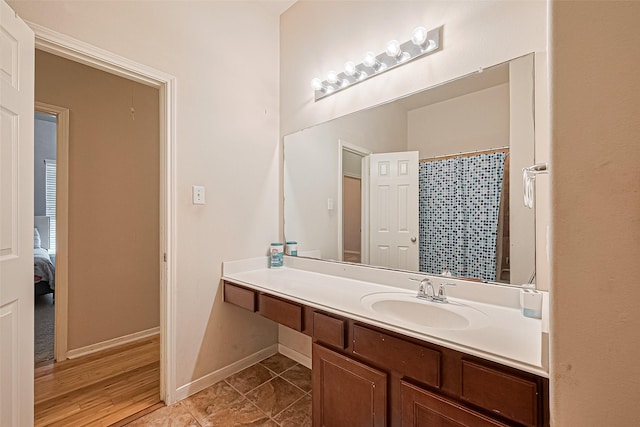 full bathroom featuring connected bathroom, a shower with shower curtain, tile patterned floors, baseboards, and vanity