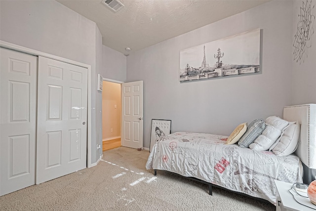 carpeted bedroom with a closet, visible vents, and lofted ceiling