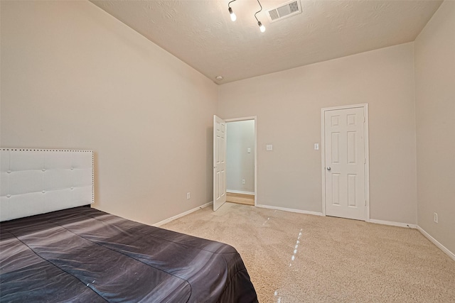 bedroom featuring lofted ceiling, a textured ceiling, baseboards, visible vents, and carpet floors