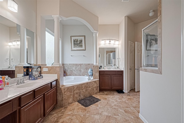 bathroom featuring a sink, decorative columns, a shower stall, two vanities, and a bath