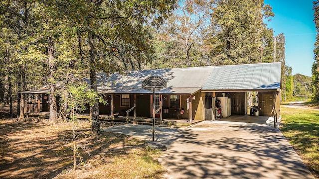 2540 Howell Rd, Corrigan, TX 75939 - view of front facade with concrete driveway, metal roof, an attached carport, and covered porch