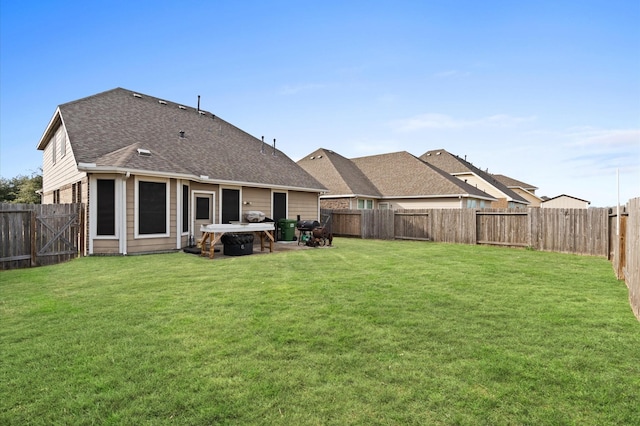 back of property featuring a yard, roof with shingles, and a fenced backyard