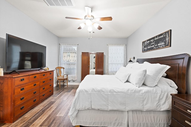 bedroom featuring a ceiling fan, visible vents, wood finished floors, and baseboards