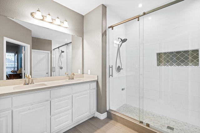 bathroom with a shower stall, double vanity, and a sink