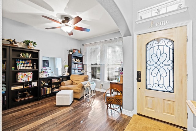 foyer entrance with a wealth of natural light, wood finished floors, a ceiling fan, and arched walkways