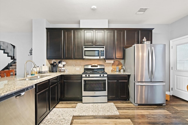 kitchen with wood finished floors, a sink, visible vents, light stone countertops, and appliances with stainless steel finishes