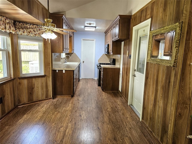 kitchen featuring a sink, stainless steel microwave, gas stove, light countertops, and dark wood-style floors
