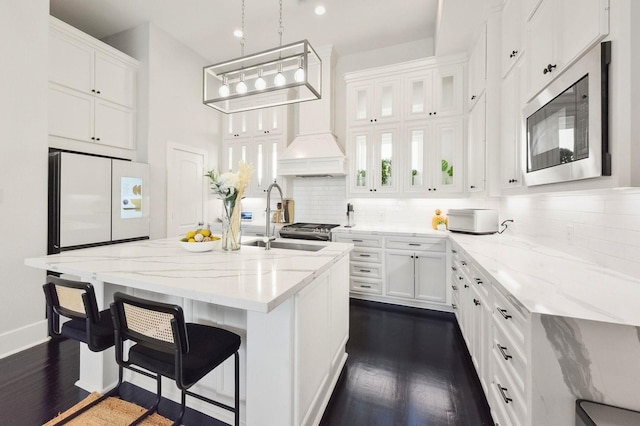 kitchen featuring stainless steel microwave, a sink, dark wood-style flooring, backsplash, and white cabinets