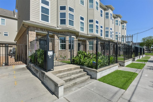 exterior space featuring brick siding, a gate, and fence