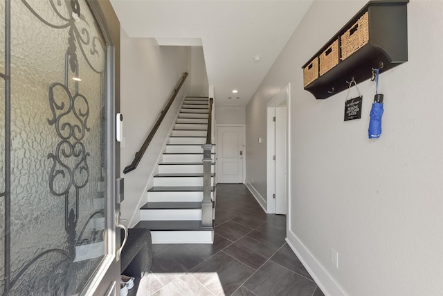 entrance foyer with recessed lighting, dark tile patterned floors, baseboards, and stairs