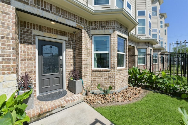 view of exterior entry with brick siding and fence