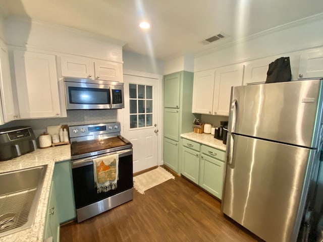 685 W 4th St, Groveton, TX 75845 - kitchen with dark wood-style flooring, visible vents, green cabinetry, stainless steel appliances, and white cabinets