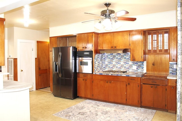 508 Texas St, Brenham, TX 77833 - kitchen featuring appliances with stainless steel finishes, brown cabinetry, tasteful backsplash, and ceiling fan