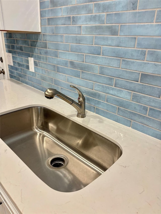1105 W Bayshore Dr, Palacios, TX 77465 - details with backsplash, light stone countertops, and a sink
