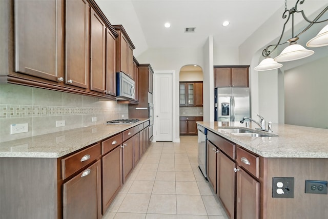 2106 Wild Peregrine Cir, Katy, TX 77494 - kitchen with stainless steel appliances, a sink, an island with sink, tasteful backsplash, and light tile patterned floors