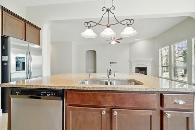 2106 Wild Peregrine Cir, Katy, TX 77494 - kitchen featuring stainless steel dishwasher, a sink, a ceiling fan, open floor plan, and light stone counters