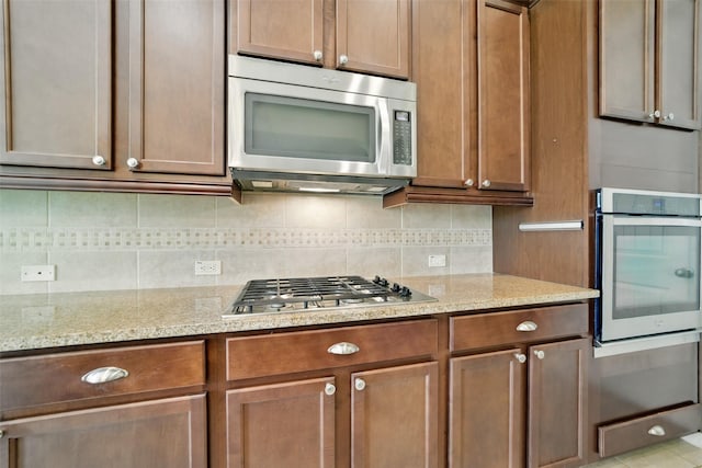 2106 Wild Peregrine Cir, Katy, TX 77494 - kitchen with stainless steel appliances, decorative backsplash, and light stone counters