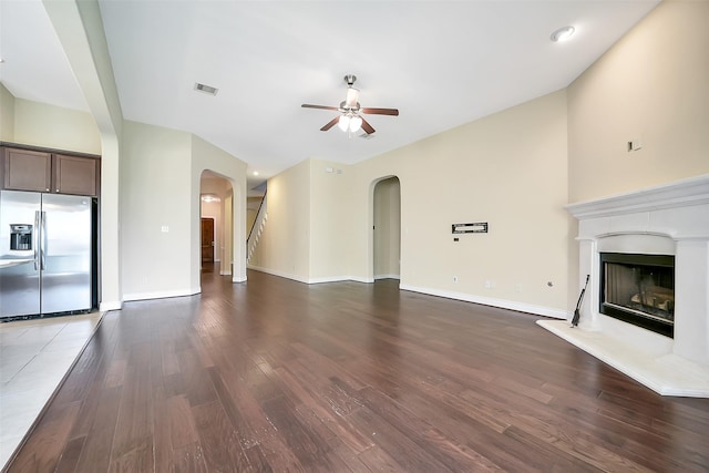 2106 Wild Peregrine Cir, Katy, TX 77494 - unfurnished living room featuring arched walkways, ceiling fan, wood finished floors, and a fireplace with raised hearth