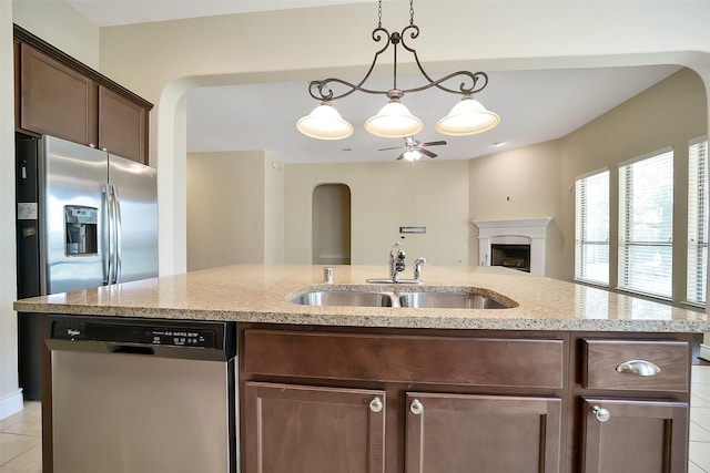 2106 Wild Peregrine Cir, Katy, TX 77494 - kitchen with stainless steel dishwasher, arched walkways, a ceiling fan, open floor plan, and light stone counters