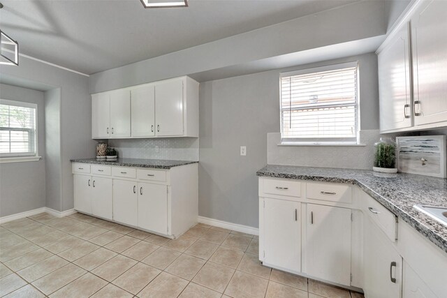 1865 El Mar Ln, Seabrook, TX 77586 - kitchen with tasteful backsplash, light tile patterned floors, baseboards, white cabinetry, and light stone countertops