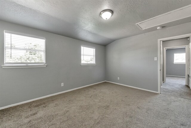 1865 El Mar Ln, Seabrook, TX 77586 - carpeted spare room with attic access, a textured ceiling, healthy amount of natural light, baseboards, and lofted ceiling