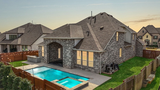 rear view of house with a fenced backyard, roof with shingles, and brick siding