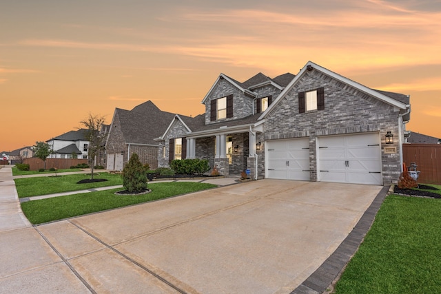 view of front of home featuring a front yard, fence, concrete driveway, stone siding, and roof with shingles