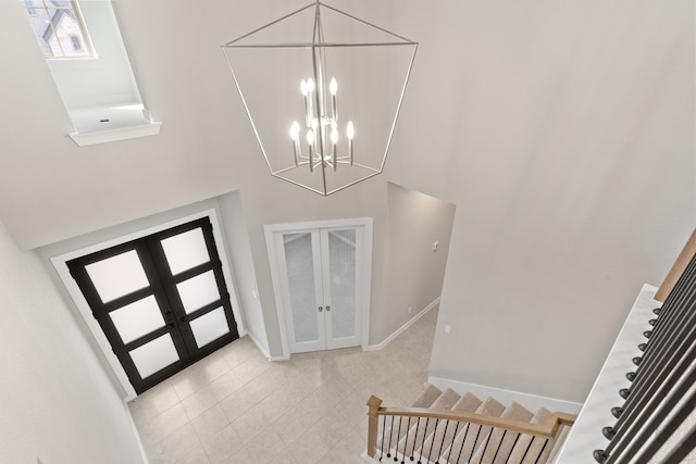 entrance foyer with light tile patterned floors, french doors, baseboards, a towering ceiling, and stairs