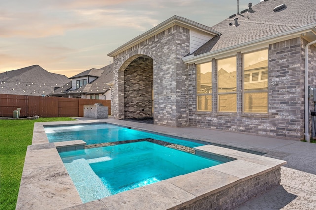 view of swimming pool featuring a pool with connected hot tub, a fenced backyard, and a patio