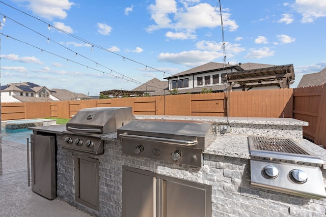 view of patio with a fenced backyard, grilling area, and exterior kitchen