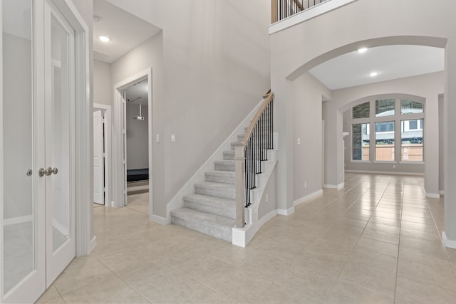 stairs with arched walkways, tile patterned flooring, and baseboards
