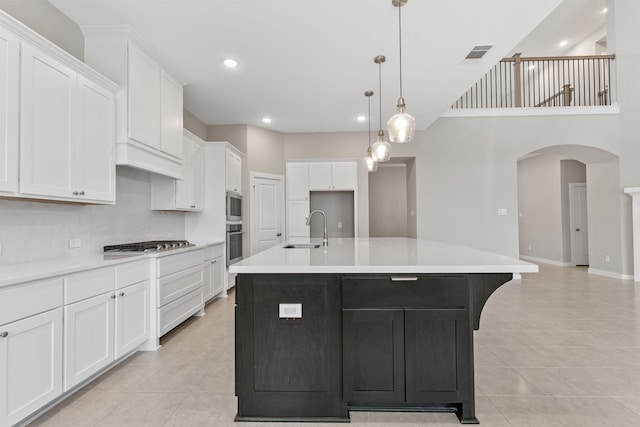 kitchen featuring a sink, light tile patterned flooring, visible vents, white cabinetry, and arched walkways
