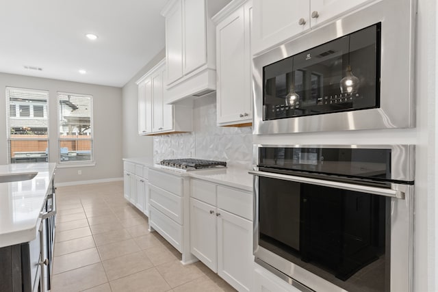 kitchen featuring stainless steel appliances, light countertops, decorative backsplash, white cabinets, and baseboards
