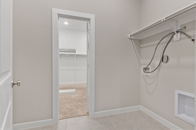 clothes washing area featuring light tile patterned floors, hookup for a washing machine, laundry area, and baseboards