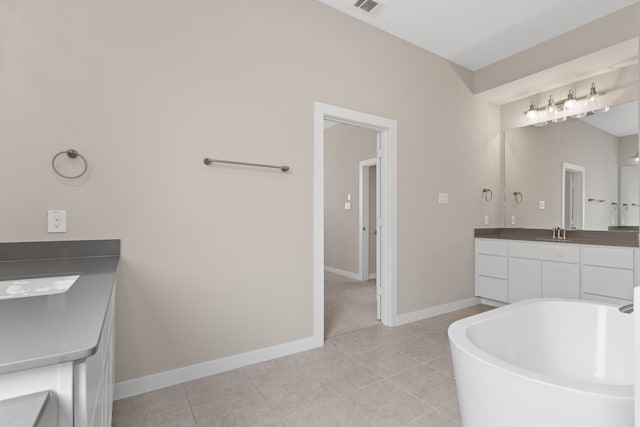 full bath with tile patterned floors, baseboards, vanity, and a freestanding tub