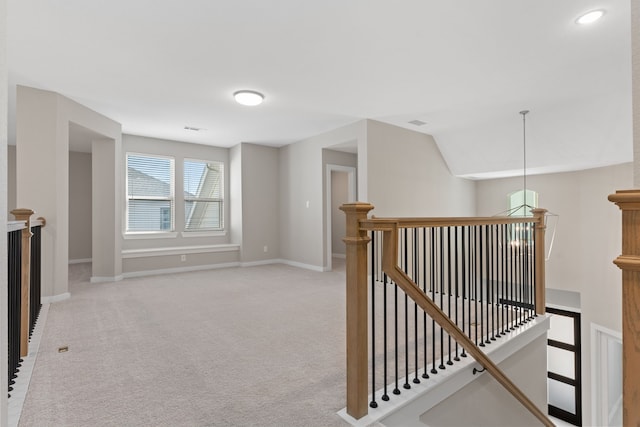hall with light carpet, an upstairs landing, and baseboards