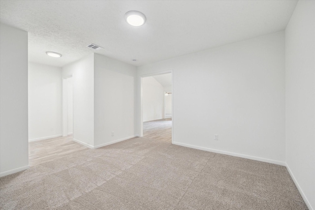 empty room featuring baseboards, visible vents, and light colored carpet