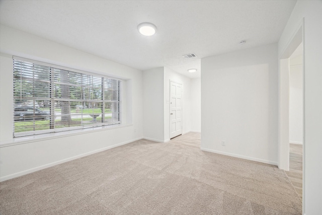 empty room with carpet flooring, visible vents, and baseboards