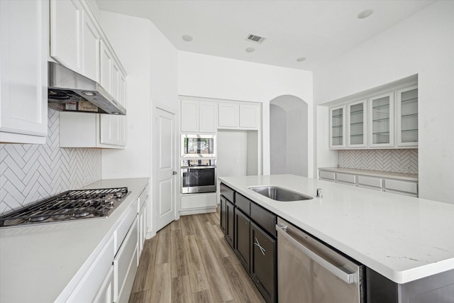 kitchen with stainless steel appliances, wall chimney range hood, visible vents, and white cabinets