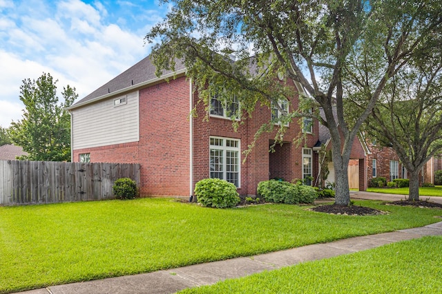view of home's exterior featuring brick siding, a yard, and fence